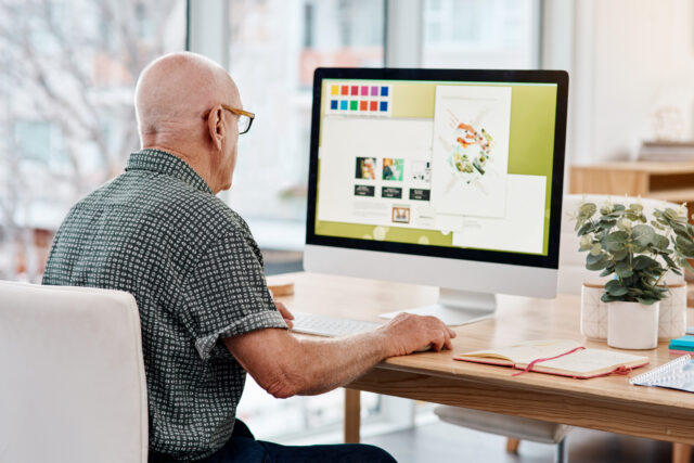 Shot of a senior creative businessman working on a computer inside his office