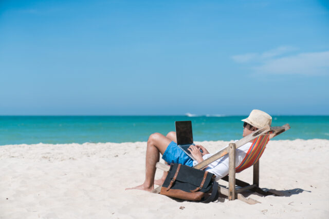 happy business man with laptop working on the beach